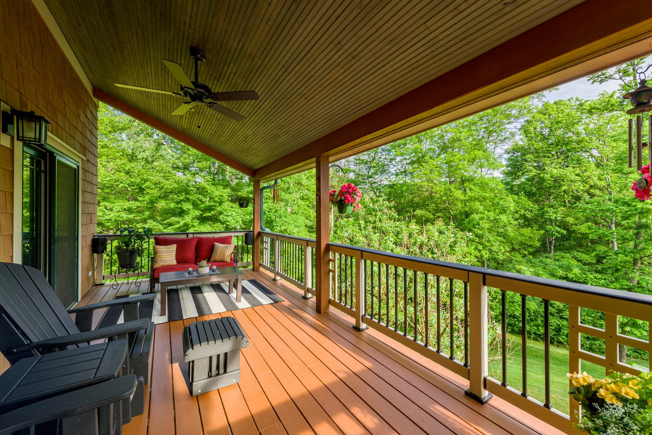 Wooden deck with chairs, table, and outdoor furniture set, surrounded by greenery.
